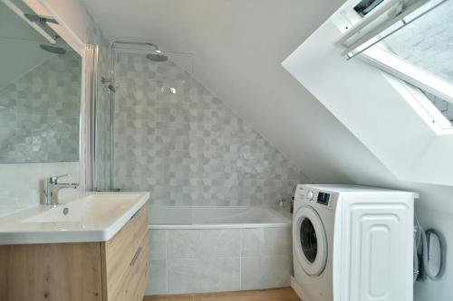 a bathroom with a sink and a washing machine at Chez Marie-Céline - Maison avec jacuzzi à 20 min du Val André in Plestan