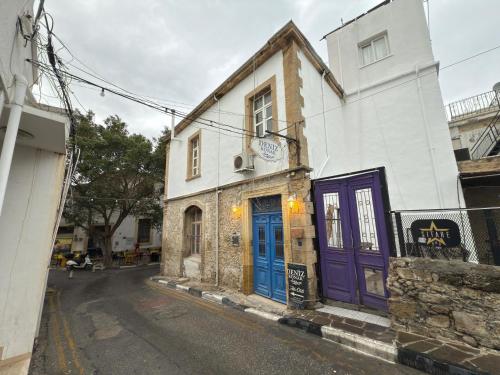 a building with blue and purple doors on a street at Deniz Konak Boutique Hotel in Kérynia