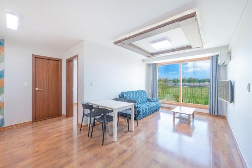 a living room with a table and chairs and a window at Gangneung Awoolim Pension in Yŏngjin 2-ri