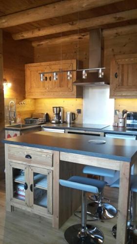 une cuisine avec un comptoir et un bar avec un tabouret dans l'établissement GITE LE CALOU AVEC JACUZZI situé à St Laurent-en-Grandvaux - du samedi au samedi uniquement, à Saint-Laurent-en-Grandvaux