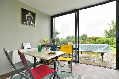 a dining room with a table and chairs on a patio at Chez Marie-Céline - Maison avec jacuzzi à 20 min du Val André in Plestan