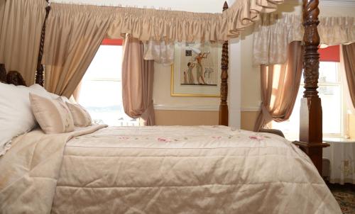 a bedroom with a canopy bed with pink curtains at The Cumberland in Llandudno