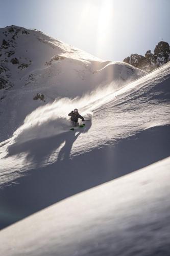 a person riding a snowboard down a snow covered slope at COMO Alpina Dolomites in Alpe di Siusi