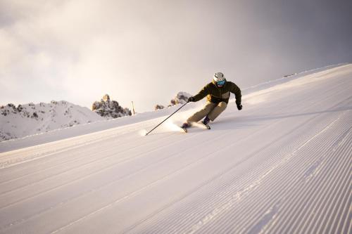 a man is skiing down a snow covered slope at COMO Alpina Dolomites in Alpe di Siusi