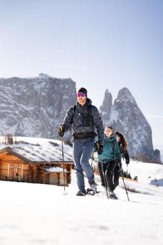 a man and a woman on skis in the snow at COMO Alpina Dolomites in Alpe di Siusi