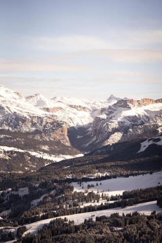 an aerial view of a snowy mountain range with a lake at COMO Alpina Dolomites in Alpe di Siusi