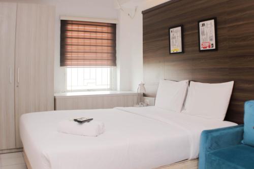 a bedroom with a large white bed and a blue chair at Cozy Stay and Tranquil Studio Patraland Urbano Apartment By Travelio in Bekasi