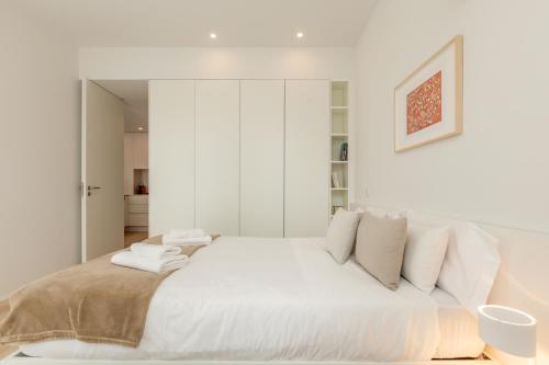 a white bedroom with a large bed with white pillows at Boavista Collection Ap for Family by Sé Apartamentos in Braga