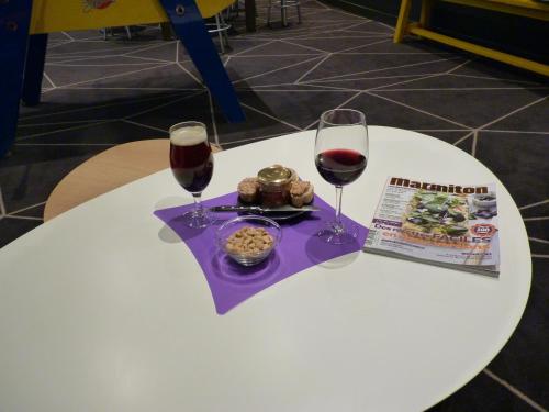a white table with two glasses of wine and a magazine at ibis Styles Roanne Centre Gare in Roanne