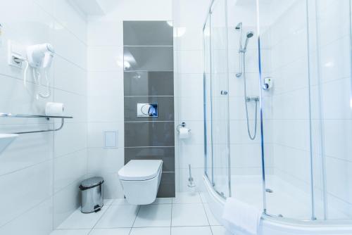 een witte badkamer met een douche en een toilet bij Hotel Austeria Conference & Spa in Ciechocinek