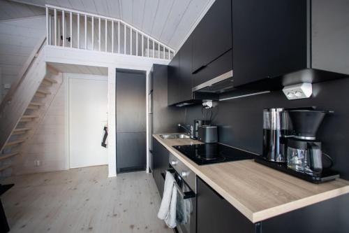a kitchen with black cabinets and a stair case at Villa Alaska in Syöte