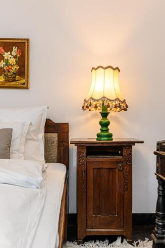 a lamp on a night stand next to a bed at Casa cu Amintiri - Authentic Cozy Cottage in Bran