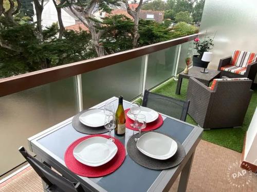 une table avec des assiettes et des verres à vin sur un balcon dans l'établissement Appartement familial de 56 m², à deux pas de la mer._2, à Pornichet