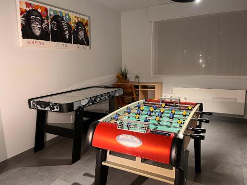 a ping pong table in a room next to a table with at vakantiewoning Baaltje in Koksijde
