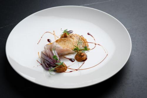 a white plate with a piece of food on it at Hammerack Hotel, SPA & Wellness in Malborghetto Valbruna
