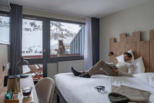 a man laying on a bed in a hotel room at Hôtel Les 2 Alpes L'Orée Des Pistes in Les Deux Alpes