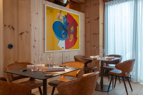 a dining room with two tables and chairs and a painting at Hammerack Hotel, SPA & Wellness in Malborghetto Valbruna
