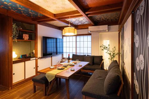 a living room with a table and a kitchen at MOMOYA tsudoi in Okayama