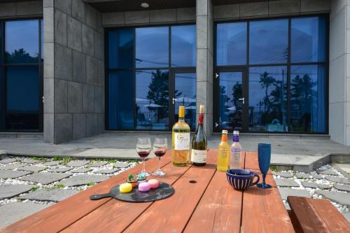 a wooden table with wine bottles and glasses on it at Yeosu Tivoli Pension in Yeosu