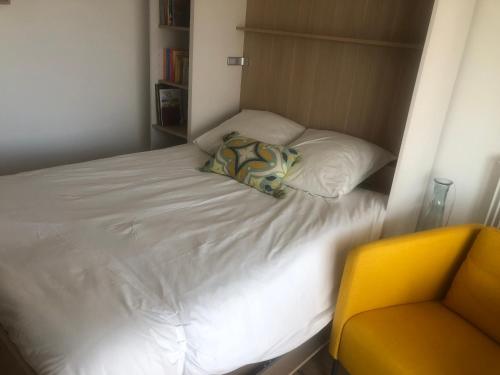 un piccolo letto in una piccola stanza con una sedia gialla di STUDIO 38 m2 Point Zéro a La Grande-Motte