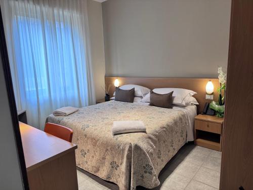 a bedroom with a bed and a large window at Hotel La Magione in Poggibonsi