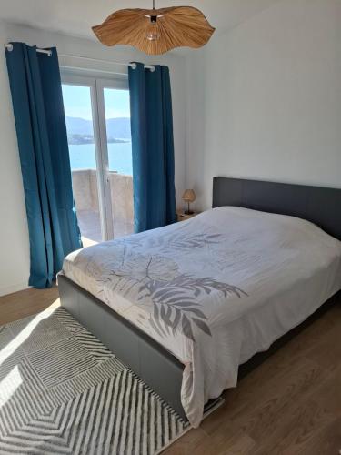 Grosseto-PrugnaにあるAppartement vue merのベッドルーム1室(青いカーテン、窓付)