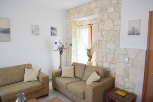 a living room with two couches and a stone wall at Sea View Maria in Fourka