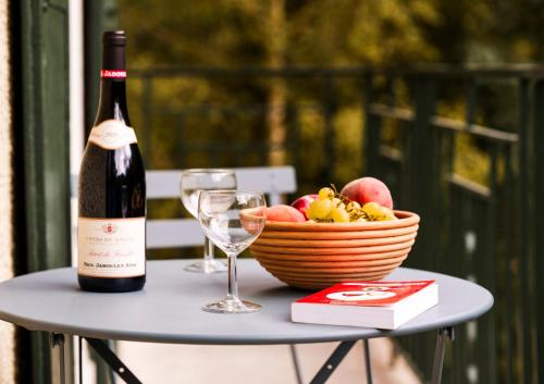 une bouteille de vin et une corbeille de fruits sur une table dans l'établissement Gîte Moucherolle - Ski - Domaine, à Villard-de-Lans