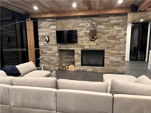 a living room with couches and a stone fireplace at Scandinavian Luxury Chalet, Hot Tub, Private Dock, Sleeps 14!! Min 32 nights in Sainte-Lucie-de-Doncaster