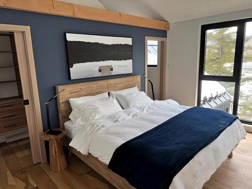 a bedroom with a large bed with a blue wall at Scandinavian Luxury Chalet, Hot Tub, Private Dock, Sleeps 14!! Min 32 nights in Sainte-Lucie-de-Doncaster