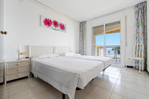 a white bedroom with a large bed and a window at Los Flamencos I in Miami Platja