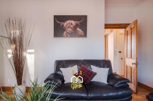 a leather couch in a living room with a bull on the wall at Albyn Retreat - SJA Stays - 1 Bed Apartment in Aberdeen