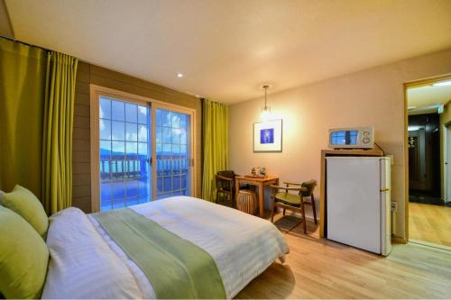 a bedroom with a bed and a refrigerator and a table at Tongyoung Mongdolhouse Pension in Tongyeong