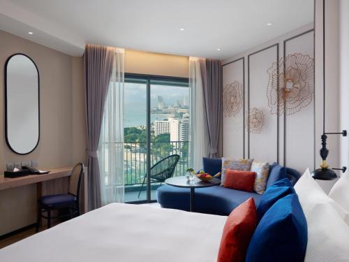 a hotel room with a bed and a blue couch at Somerset Pattaya in Pattaya Central
