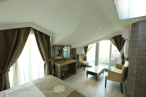 a bedroom with a bed and a desk and windows at Unluselek Hotel in Anamur