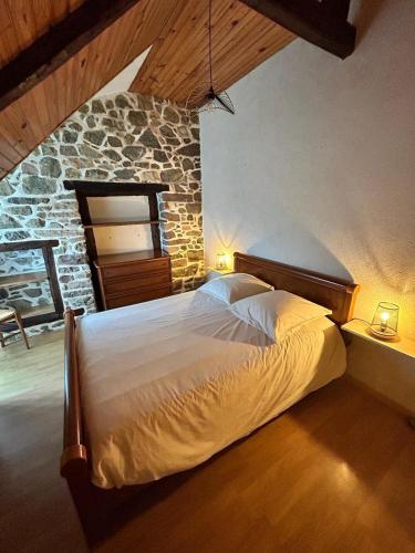 une chambre avec un grand lit dans un mur de pierre dans l'établissement La maison du malteur vue mer, à Plurien