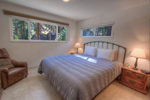 a bedroom with a bed and a chair and two windows at Foothill Folly home in Zephyr Cove