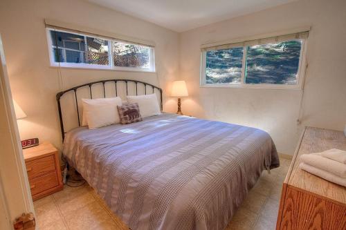 a bedroom with a large bed and two windows at Foothill Folly home in Zephyr Cove