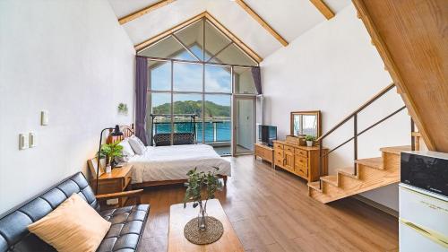 a bedroom with a bed and a couch in a room at Tongyeong Maremio Oceanview Pension in Tongyeong
