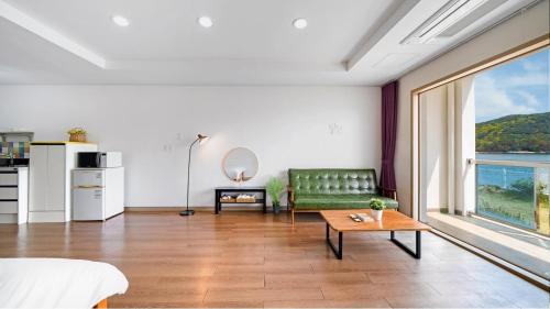 a living room with a green couch and a table at Tongyeong Maremio Oceanview Pension in Tongyeong