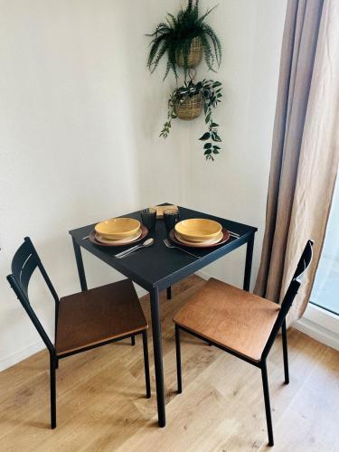 a black table with two chairs and plates on it at Le Bocal - Private Parking - Wi-Fi in Gradignan