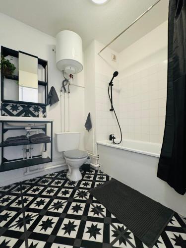 a bathroom with a black and white tile floor and a toilet at Le Bocal - Private Parking - Wi-Fi in Gradignan