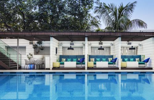 a pool with blue and yellow furniture next to a building at The Park Kolkata in Kolkata