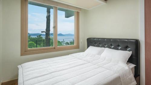 a bedroom with a bed with a large window at Yeosu falling in blue ocean view pension in Yeosu