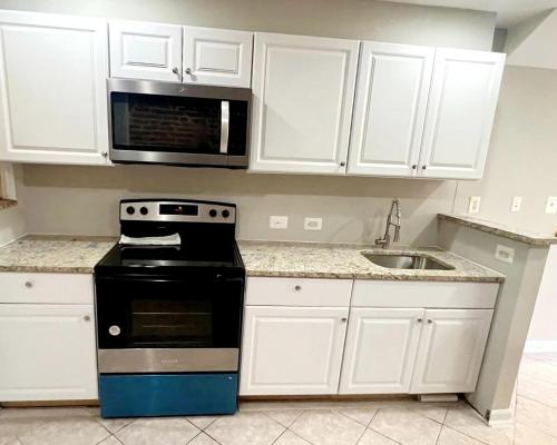 a kitchen with white cabinets and a stove and a sink at Whole House Walking Distance Stadium Free Parking in Baltimore