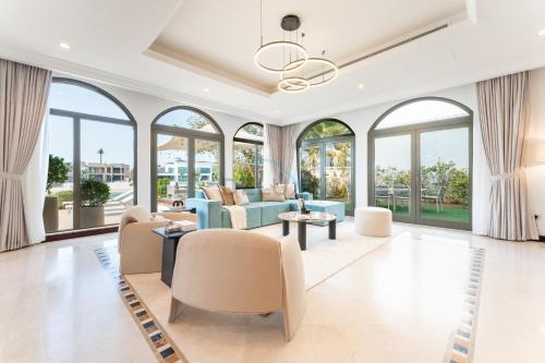 a living room filled with furniture and windows at Beachfront 6BR and Assistant's Room Villa with Private Pool, Palm Villa, Palm Jumeirah by Deluxe Holiday Homes in Dubai