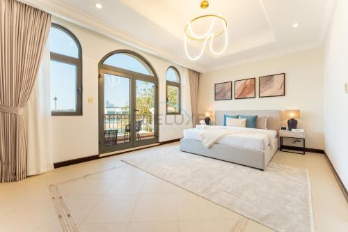 a bedroom with a white bed and large windows at Beachfront 6BR and Assistant's Room Villa with Private Pool, Palm Villa, Palm Jumeirah by Deluxe Holiday Homes in Dubai