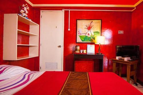 ein rotes Schlafzimmer mit einem Bett und einem Schreibtisch in der Unterkunft St Nicolas Inn CDO City Center in Cagayan de Oro