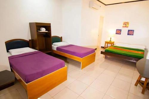 ein Zimmer mit drei Betten in einem Zimmer in der Unterkunft St Nicolas Inn CDO City Center in Cagayan de Oro