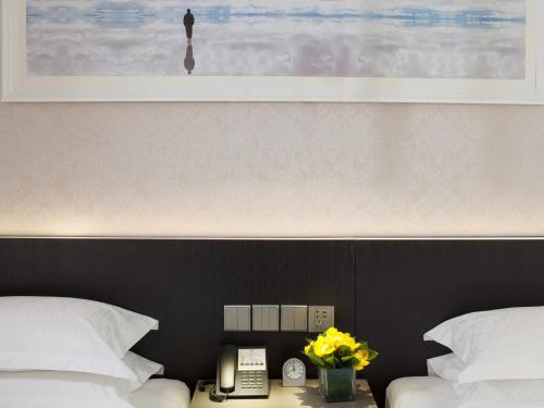 a bedroom with two beds and a phone and flowers at Beijing Landmark Towers in Beijing